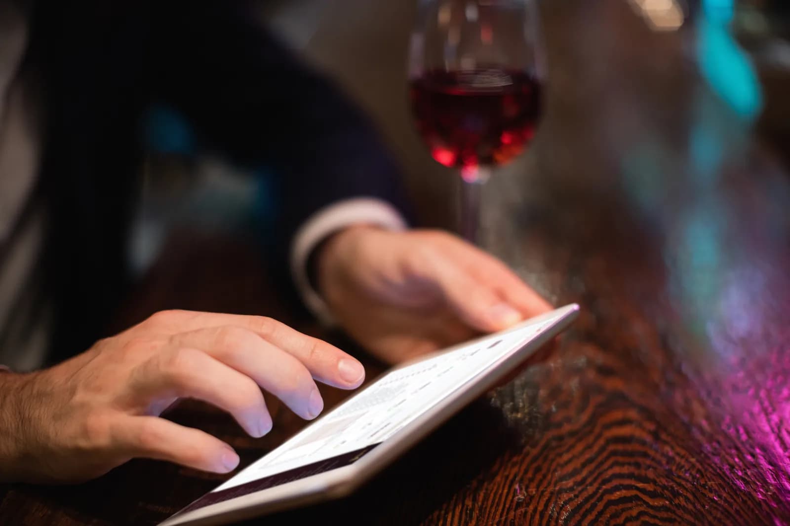 Personne utilisant Caves Explorer sur sa tablette Apple, au comptoir d’un bar à vin